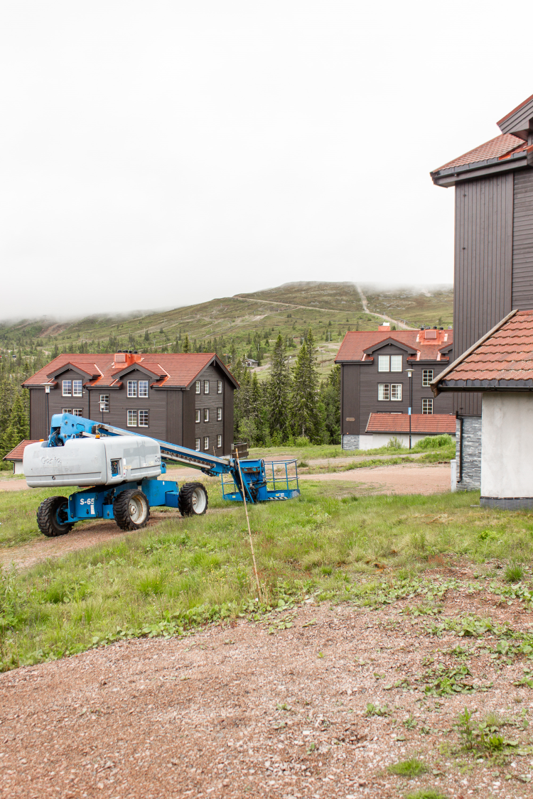 vy over hus i bunn av en slalombakke, en tåkete sommerdag