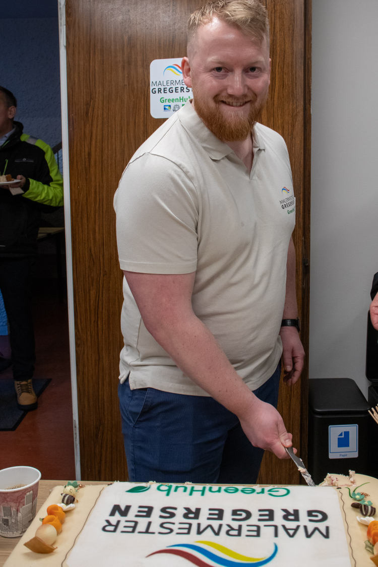 mann i t-skjorte skjærer opp et stykke kake