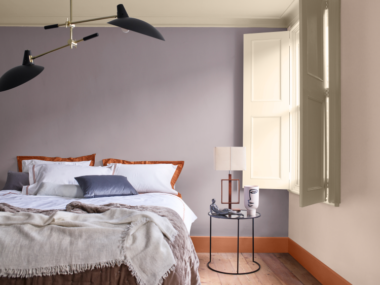 soverom med seng mot lilla vegg