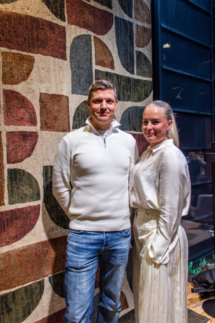 yngre mann og dame foran teppe som henger i taket