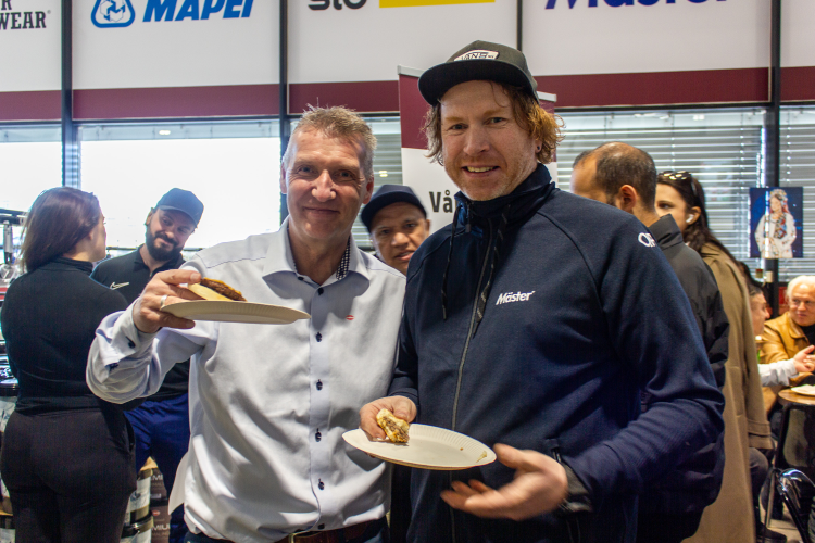 to menn ser inn i kamera, spiser kake i proffbutikk for maling