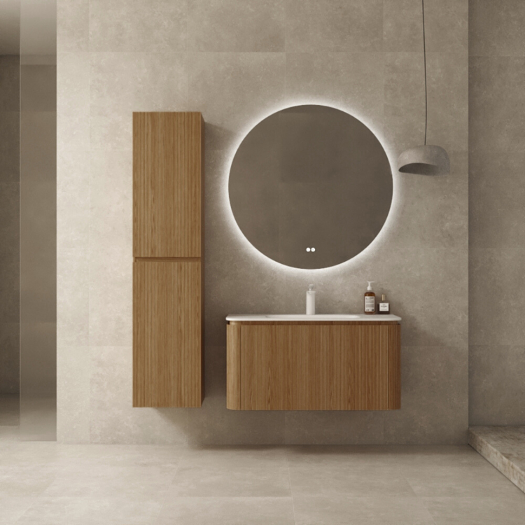 Baderom med beige fliser og innredning i naturfarget eik, servant og høyskap. Et rundt speil over servanten. 