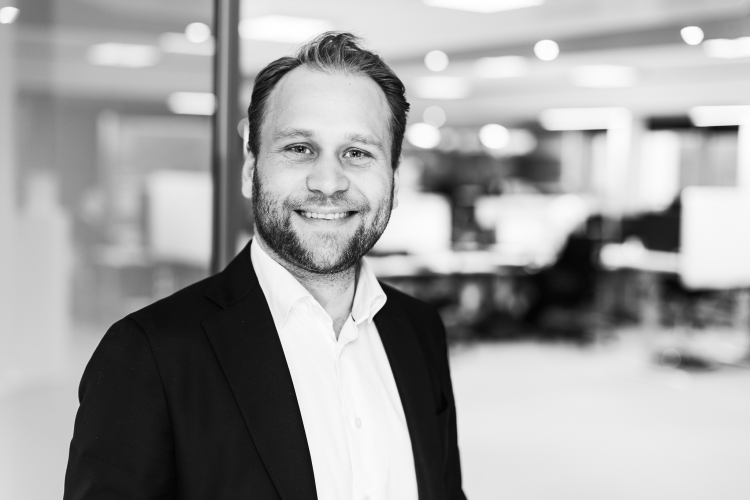 sort/hvitt bilde av smilende mann i skjorte og dressjakke