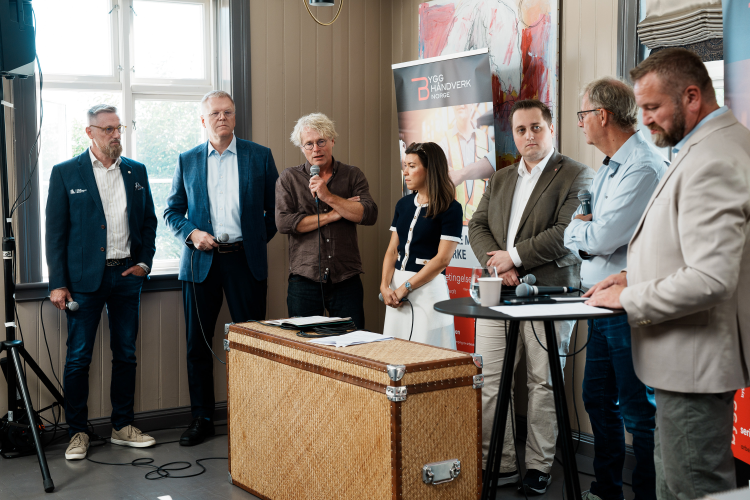 mann i brunt taler i paneldiskusjon