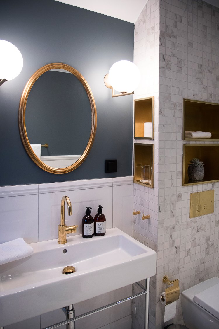 Bad med blåmalt vegg og gyldne detaljer