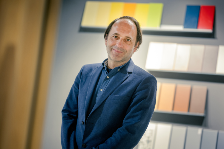 Mann i blå dressjakke og skjorte foran vegg med fargeprøver