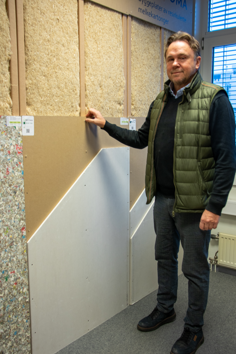 mann viser vegg med plater og isolasjon