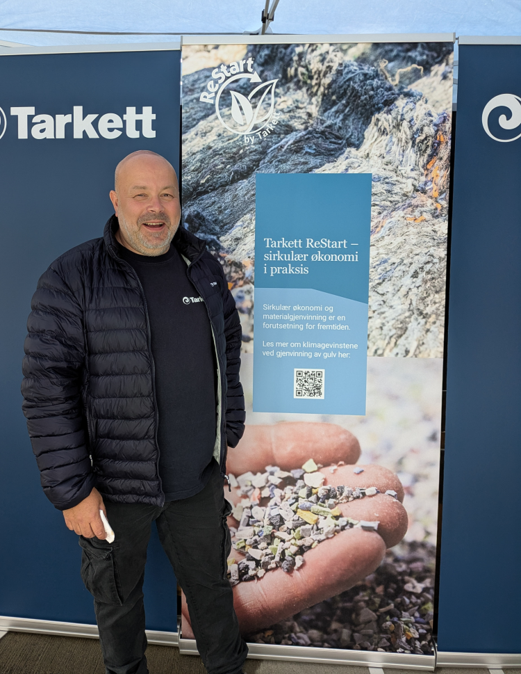 smilende mann foran plakat