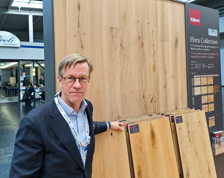 mann i blå skjorte og dressjakke mot stativer med parkettgulv