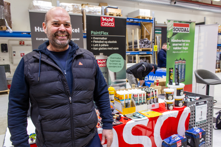 mann i blå boblekjakke foran bord med Casco- og Sika-produkter