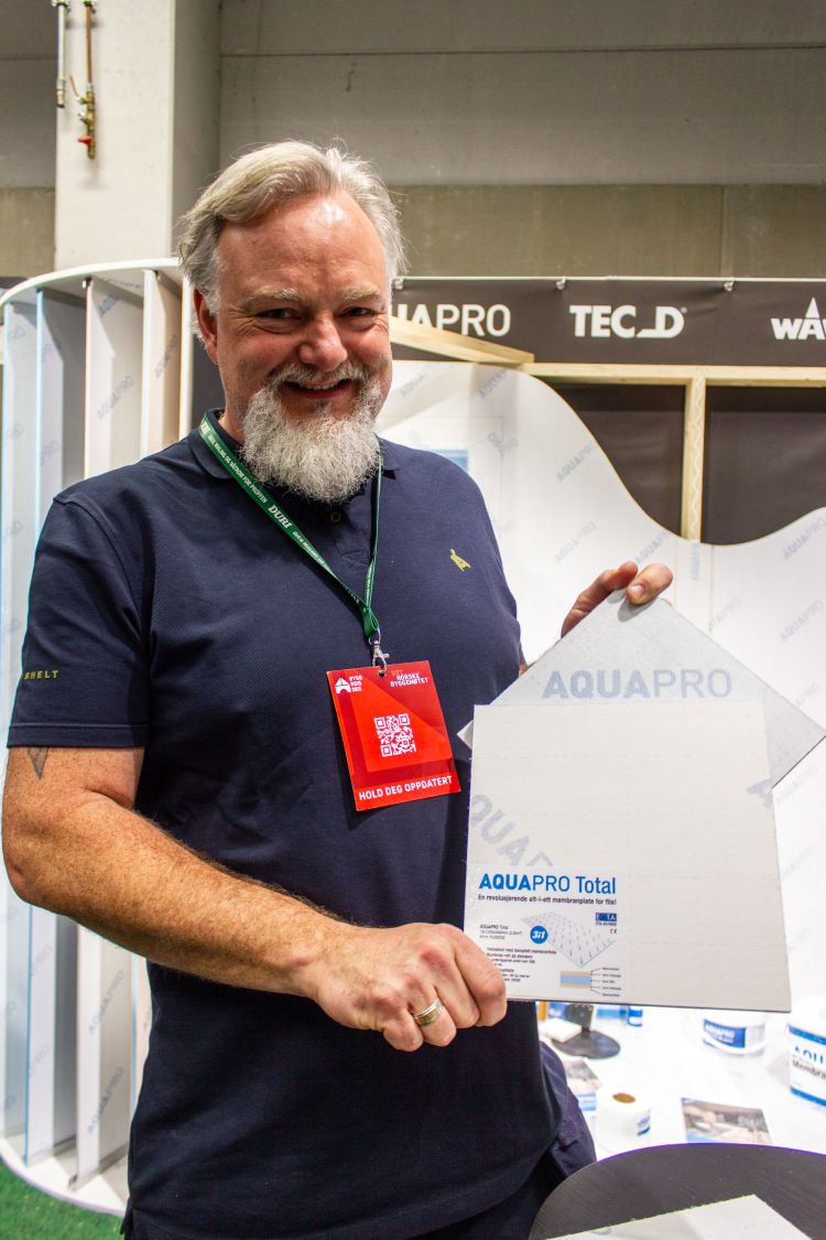 mann med skjegg og blå skjorte holder frem en prøve på en membranplate