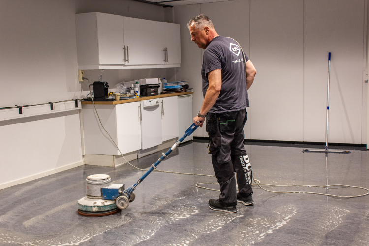 mann bruker skuremaskin på gulv med linoleumbelegg