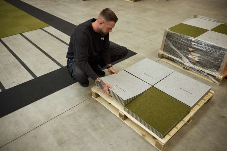 mann i sort arbeidsklær laster av teppefliser fra en lastepall 