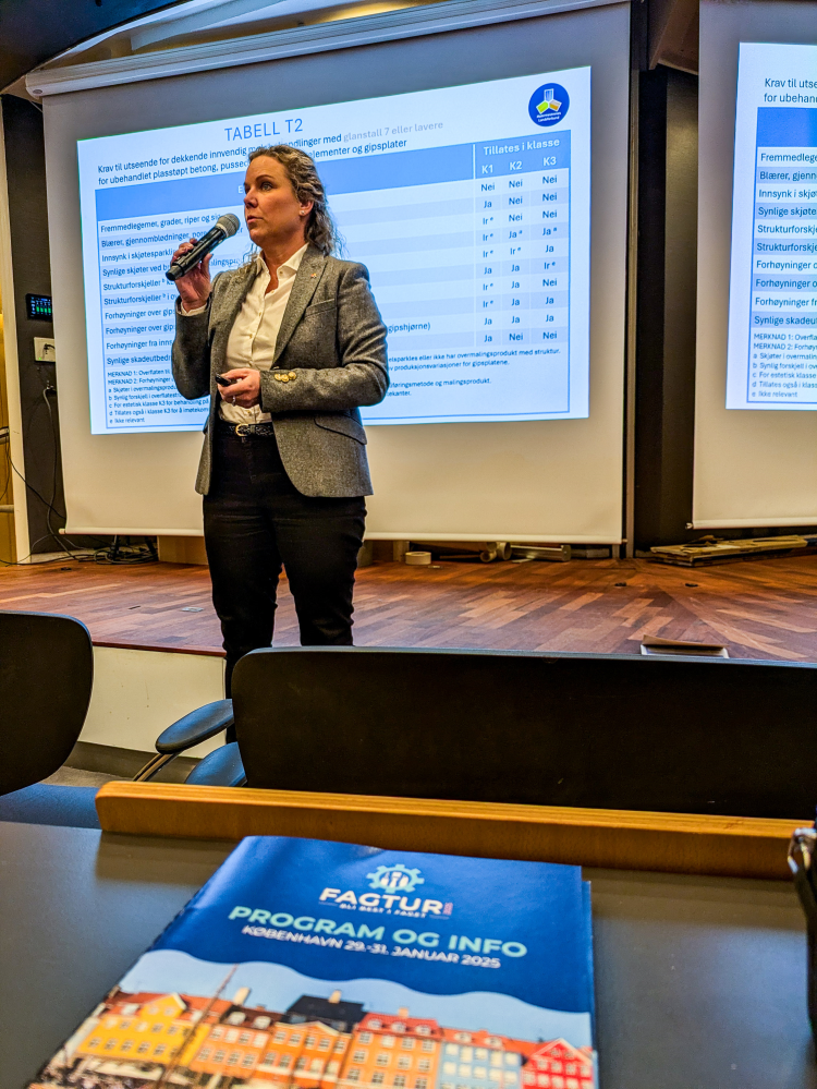 dame snakker i mikrofon foran stor lystavle