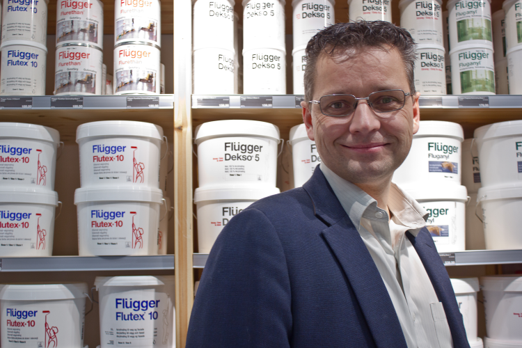 mann foran malingbokser i hyller