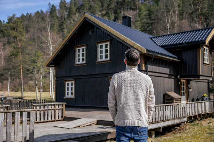 Person står og titter på et hus.