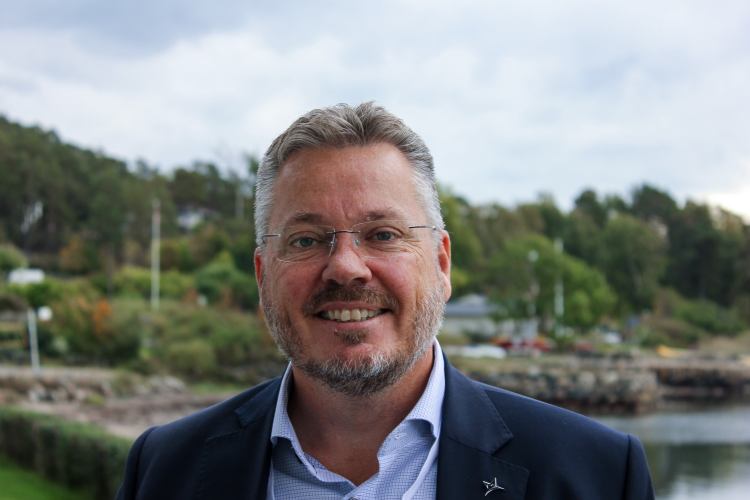 mann i blå dress foran sjøen