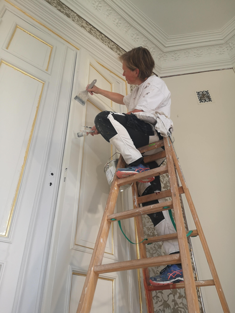 Malermester Anne Louise Gjør maler dør på Gaarder gard i Elverum.