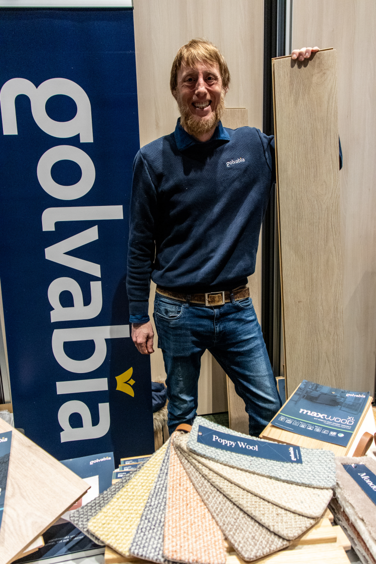 smilende mann med skjegg viser gulvprøver 