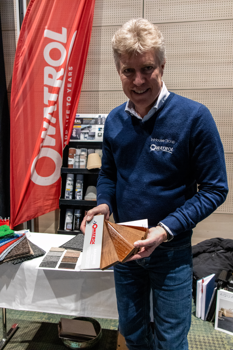 mann i blå genser viser prøver på oljebehandling fra Owatrol