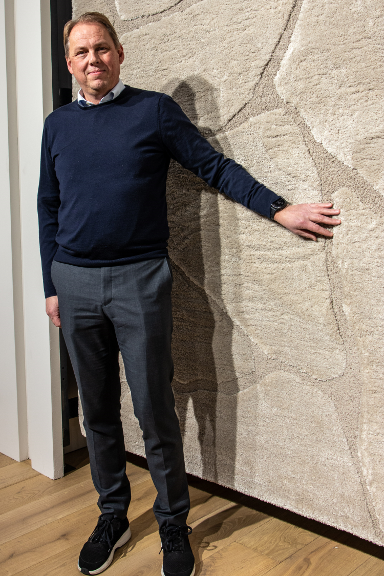 mann holder frem et hengende teppe 