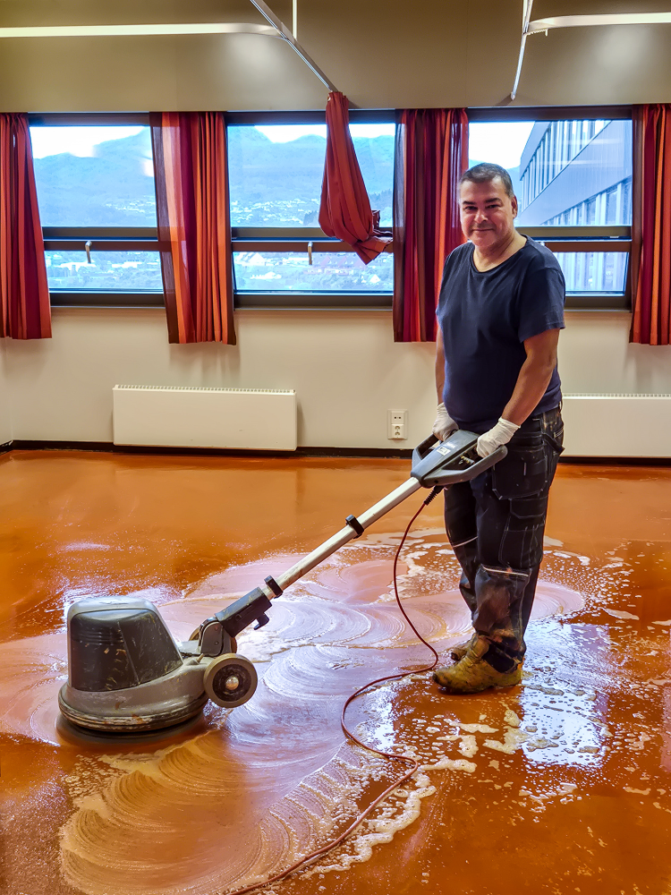 mann skurer oransje linoleumbelegg 