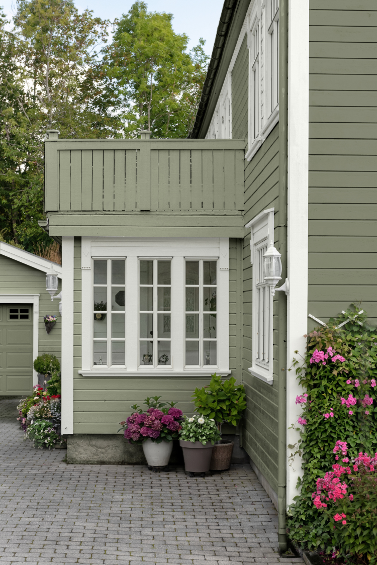 grønt hus hvite detaljer balkong blomster