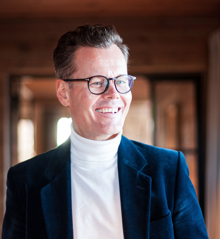 mann i blå velurdressjakke og hvit pologenser smiler