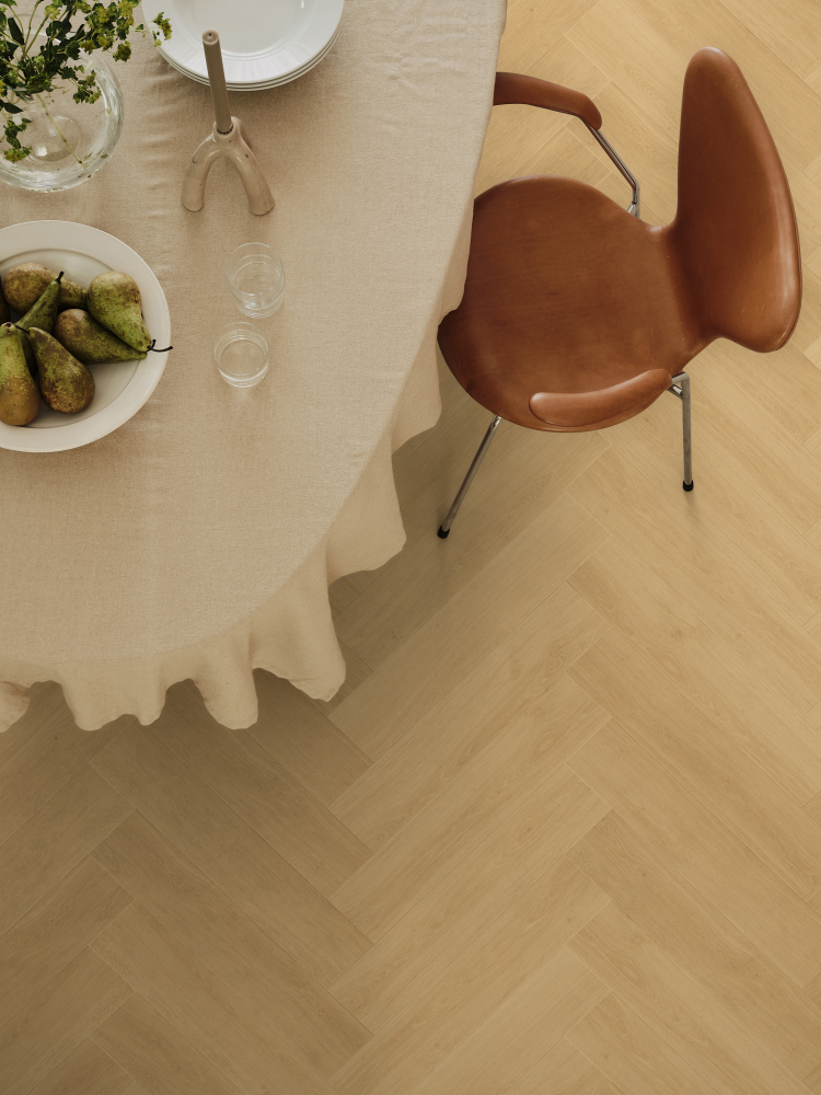 fiskebensmønstret gulv under et spisebord med duk og en brun stol