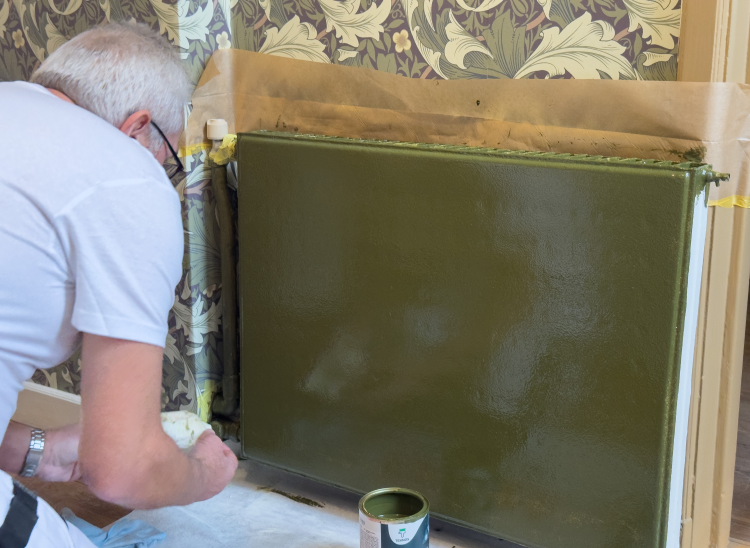 Per Morten Kværne hos Teknos maler en radiator grønn.