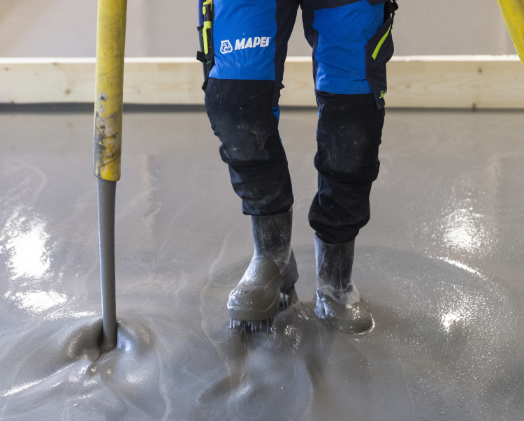 avrettingsmasse legges ut med pumpebil, mann i slagstøvler 