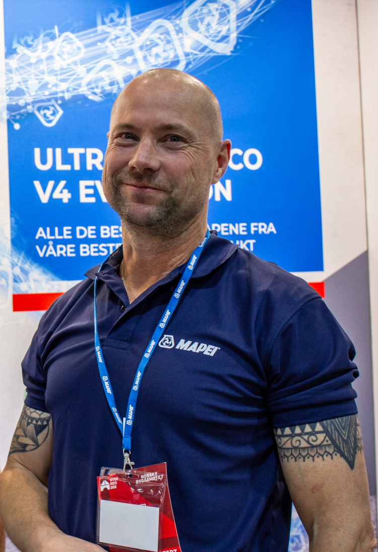 mann i blå t-skjorte med messebadge runt halsen