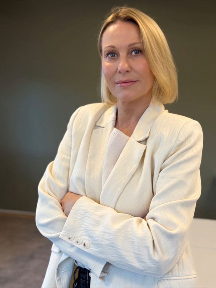 Dame med lyst hår hvite klær mot mørk bakgrunn