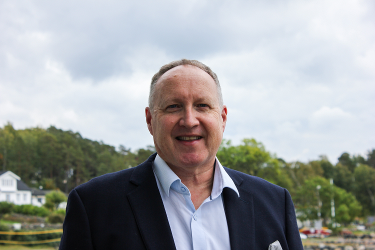 mann i blå skjorte og kavaj foran havet