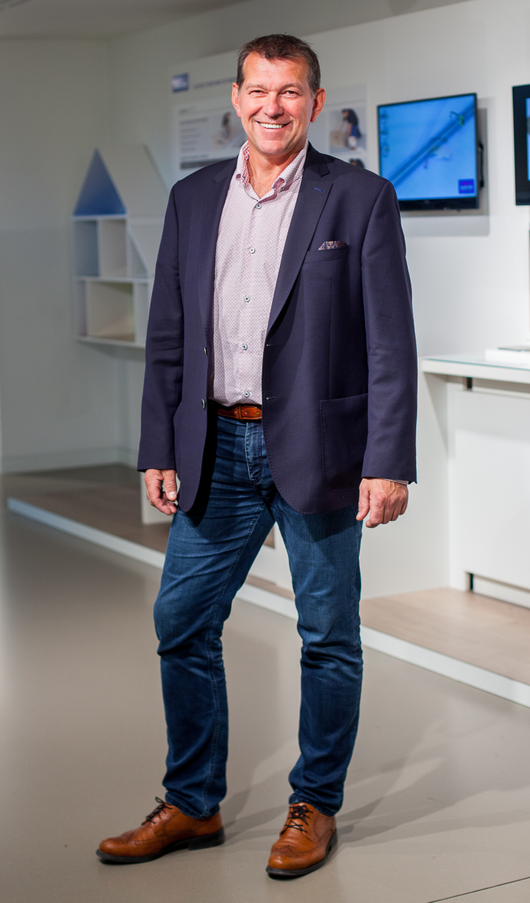 mann i blå dress foran bilder og hvit vegg