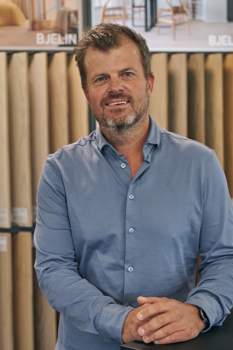 mann med kort skjegg foran tregulvprøver