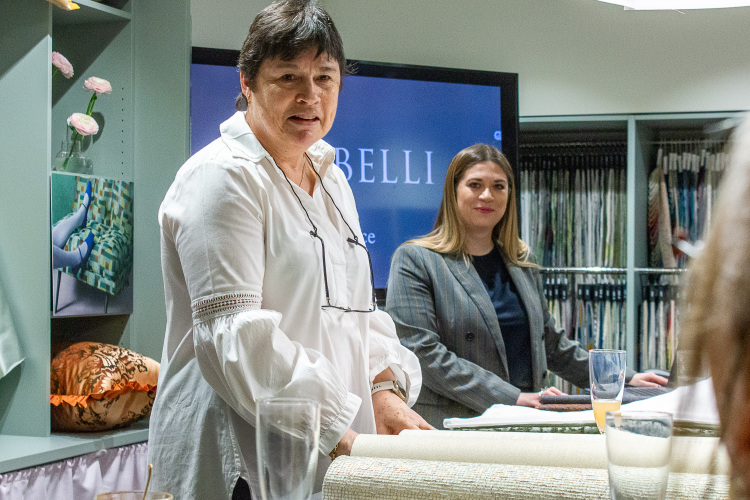 dame i hvit bluse foran dame i dressjakke i showrom med tekstil