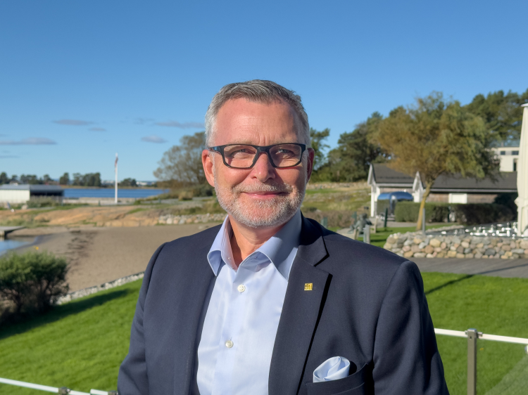 mann i blå skjorte og dressjakke, portrettfoto tatt utendørs 