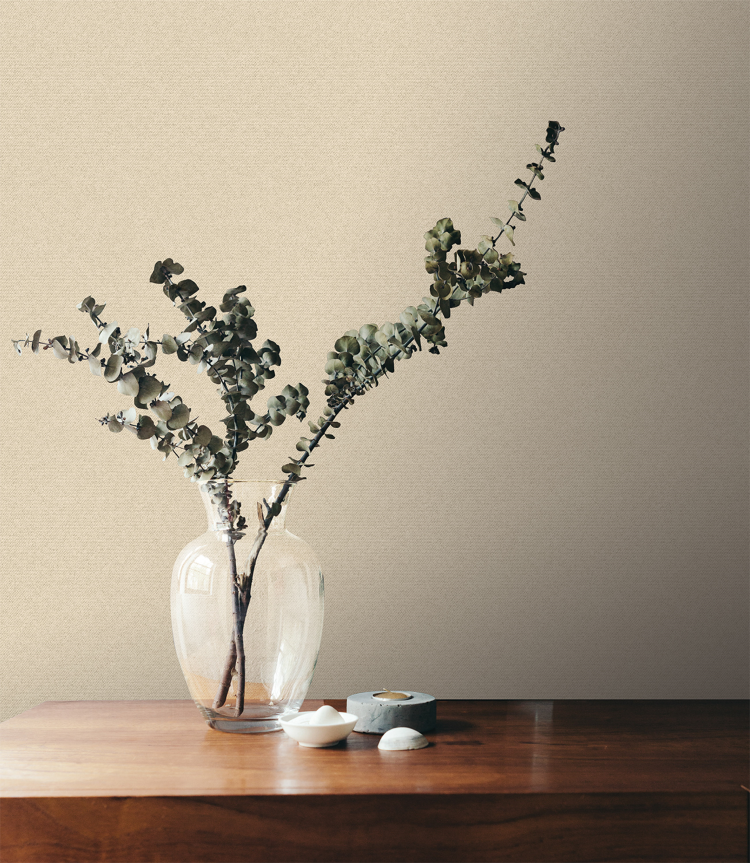 beige vegg med vase med grønne kvister i