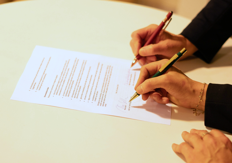 to hender skriver under på papir 