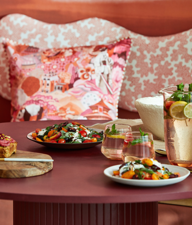 rød vegg, rosa blomstrete puter, mat på bord 