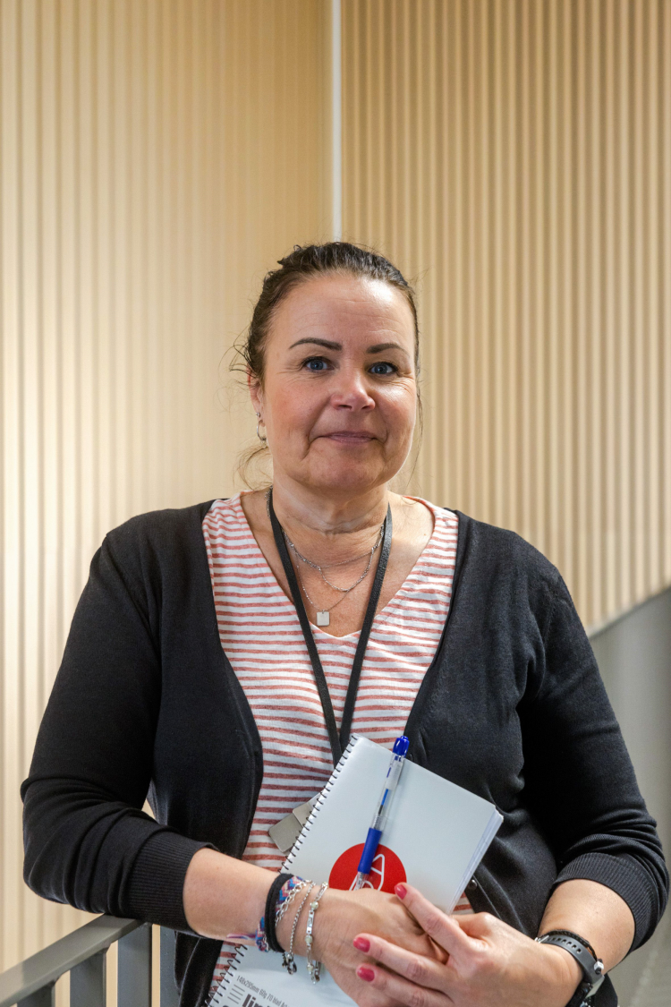 dame i stripete genser og sort cardigan foran vegg