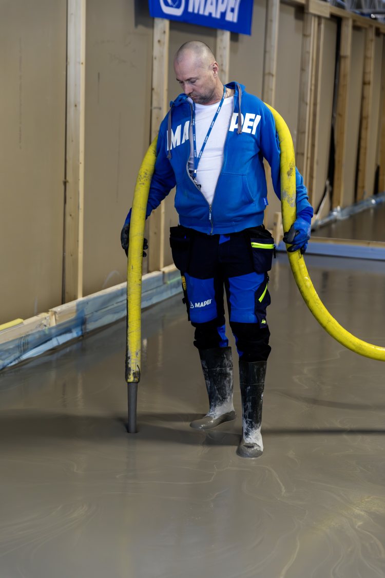 mann med gul slange i våt betong