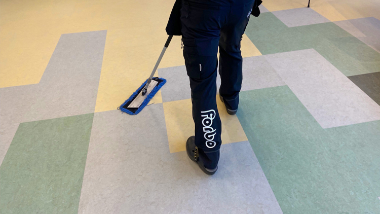 mann som vasker linoleumsgulv med tørrmopp
