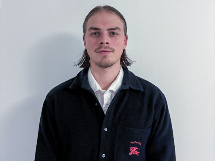 mann med hvit skjorte og sort cardigan mot hvit bakgrunn