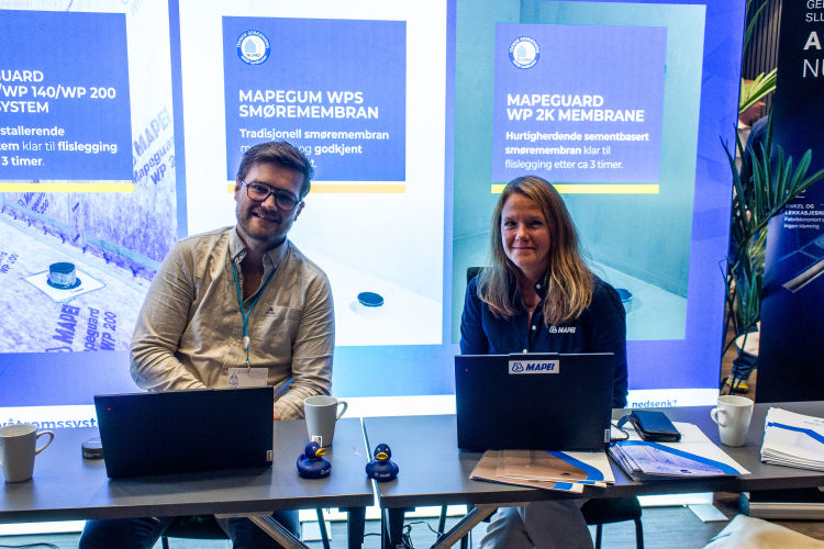 ung mann og dame sitter på messestand for Mapei