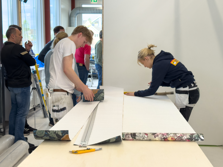 To av utøverne som skal delta i NM står og skjærer ut tapet.