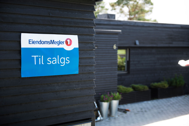 sort enebolig med til-salgsskilt